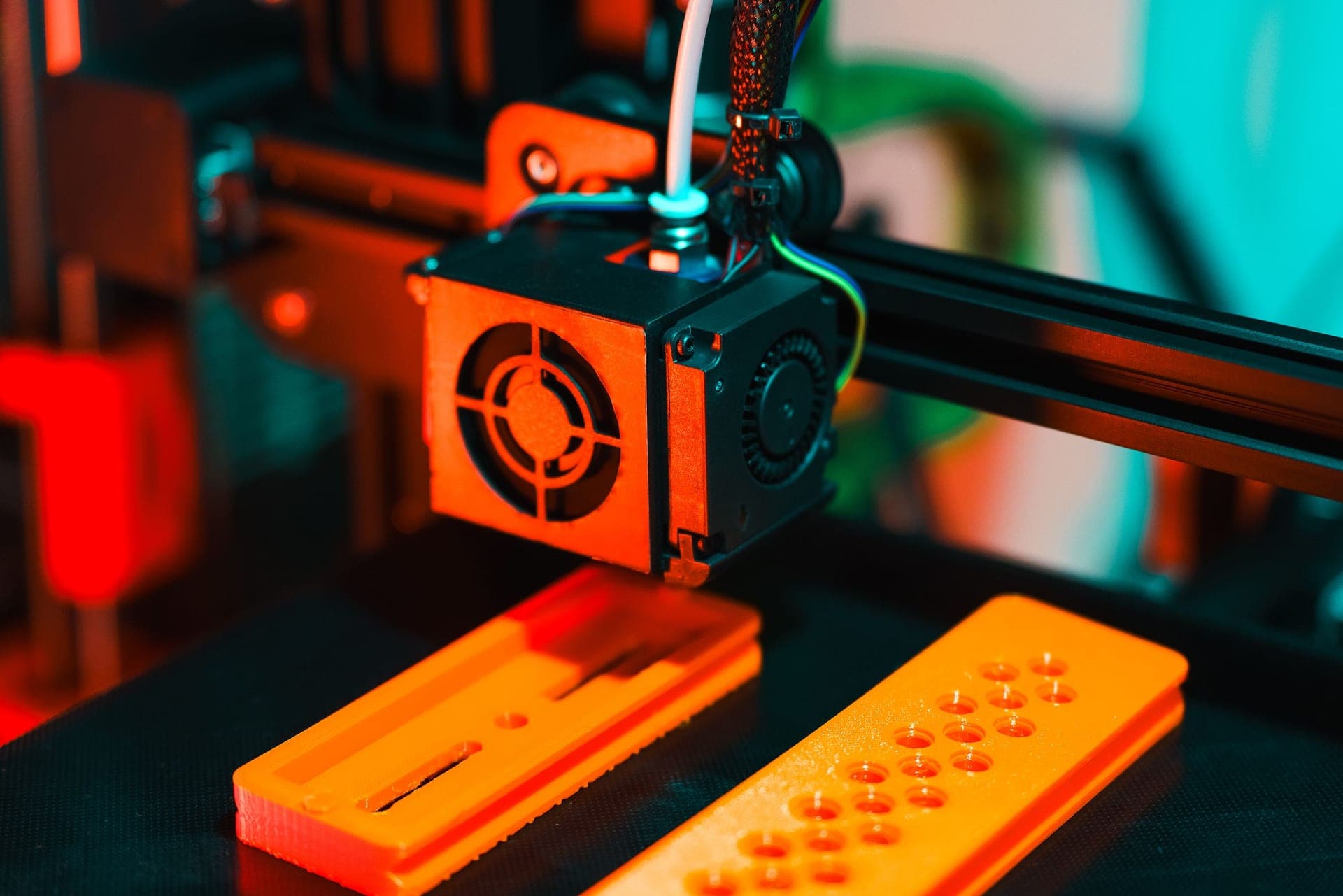 A dark engineering-grade printed bracket beside a spool